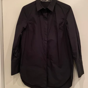 Second Female skjorta - Helt ny skjorta från Second Female. Skjortan har en klassisk krage och knappar framtill. Perfekt för en minimalistisk look eller för kapselgarderoben.                                        Modell: Larkin                                               Nypris: 949kr