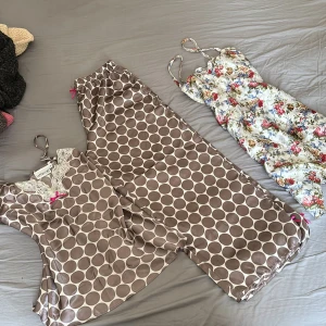 ALLT för 300kr - Säljer en somrig blommig klänning/nattlinne med smala axelband och en prickig pyjamas från Cappuccini. Klänningen har ett färgglatt blommönster medan pyjamasen är brun med stora vita prickar och spetsdetaljer vid halsen.