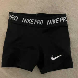 Svarta träningsshorts från Nike - Snygga svarta träningsshorts från Nike med elastisk midja och vit logga. Stl Xs