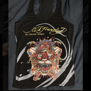 Svart linne från Ed Hardy - Snyggt svart linne från Ed Hardy med ett färgglatt tigertryck och guldtext på framsidan.