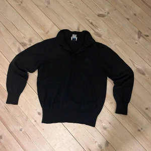 Svart tröja från Vivienne Westwood - Säljer en stilren svart tröja från Vivienne Westwood, tillverkad i Italien. Tröjan har långa ärmar och en diskret broderad logotyp på bröstet. Perfekt för en elegant och avslappnad look. Passar liten på mig som är 173cm.  Står  XL men passar som en XS. Är öppen för bud. 