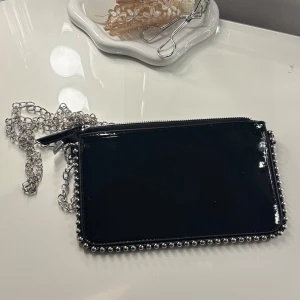 Svart handväska - Jätte snygg handväska, helt oanvänd. Ganska liten, och rymmer inte särskilt mycket. Passar perfekt vid utgångar eller festligare tillfällen! (Sista bilderna ger ett perspektiv på dess storlek!)