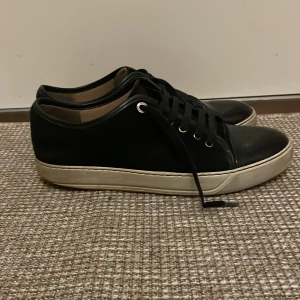 Svarta sneakers från Lanvin - Snygga svarta sneakers från Lanvin med vit sula och klassisk snörning. Perfekta för en stilren look. Uk 8
