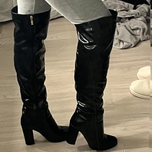 Svarta lack stövlar  - As Snygga svarta lack stövlar med hög klack och dragkedja på sidan. Perfekta för utgång 😍🥰☺️lite repor på insidan av dom men syns inte då fokuset är på att dom glänser så! Dom är varmfodrade också 