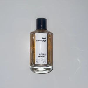 Mancera Roses Vanille Eau de Parfum - Elegant parfymflaska från Mancera med doften Roses Vanille. Flaskan är genomskinlig med en svart kork och en vit etikett. Innehåller 120 ml av en lyxig och söt doft med inslag av ros och vanilj.