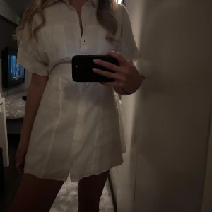 Vit klänning från Zara - Säljer en stilren vit klänning från Zara med korta ärmar och knappar framtill