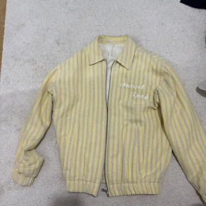 Jacka zara - Snygg gul och vit randig jacka från Zara . Jackan har dragkedja och långa ärmar, perfekt för vår och sommar. Den har en klassisk krage och elastiska muddar.