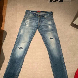 Blå jeans med slitningar - Säljer ett par blå Jack and jones jeans med coola slitningar 
