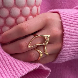 Olympia callidora ring  - Säljer denna snygga och moderna guldpläterade ring med en unik, böljande design från Olympia. Ringer är justerbar och passar alla. Aldrig använd och är i nyskick. Perfekt för att ge en stilren touch till din outfit. Kommer i en elegant röd presentask med rosett. Nypris: 100kr säljer för 49kr.