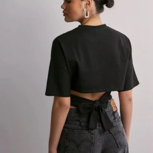 Svart Nelly T-shirt  - Jätte snygg T-shirt från Nelly med knyte i midjan som man kan knyta både fram och bak, köptes för 249kr i somras men har endast användt 2 ggr, storlek M men efter sol att man knyter den så passar den mindre också, jag har xs/s i vanliga fall🤗