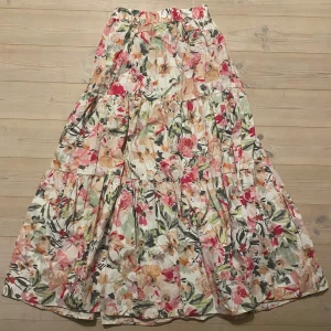 Blommig långkjol från Gina Tricot - Säljer en vacker blommig långkjol från Gina Tricot. Kjolen har ett färgglatt mönster med inslag av rosa, grönt och beige. Perfekt för en somrig look!