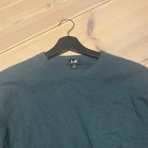 Mörkgrön kashmirtröja från Uniqlo S - Säljer en  mörkgrön kashmirtröja 100% Kashmir ,från Uniqlo i storlek s , tröjan är i toppkvalite förutom de lilla hål som visas på sista bilden. Nypris runt 1300 hålet går väldigt lätt att fixa