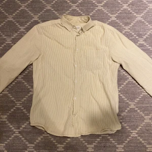 Randig skjorta från These Glory Days - Snygg och stilren randig skjorta från These Glory Days i en ljusgul nyans. Skjortan är tillverkad i 100% bomull och har långa ärmar samt knappar framtill. Perfekt för en avslappnad men ändå uppklädd look. Riktigt bra för en fett sommar outfit☀️💦. Storlek S men passar både M och S 