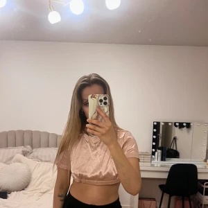 Rosa satin croppad topp - Snygg rosa croppad topp i satin med korta ärmar. Knytband i ryggen st XS. Behöver strykas men är i nyskick