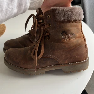 Panama Jack 03 igloo bruna - Aldrig använda, nya utan prislapp, men har legat i en skokartong bortglömda i fyra år. Dem är i brunt fårskinn med grått lammull och lammullsfoder innuti hela skon, varma och vattentäta. Har original skokartong som skorna kom i, nypris 2695 på zalando.