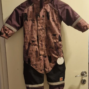 Mönstrad regnjacka från PAX - Säljer en superfin regnoverall från PAX i storlek 86-92. Overall är lila med ett gulligt djurmönster i olika färger. Den har långa ärmar och reflexdetaljer för extra säkerhet. Perfekt för regniga dagar med sitt WR system 3000 som håller dig torr. Overall har dragkedja och justerbara ärmslut med kardborreband.