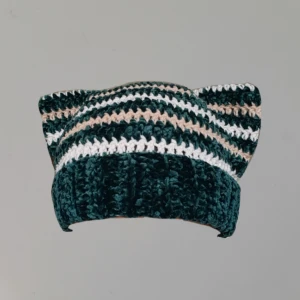 Randig virkad mössa | Cat ear beanie handmade - Säljer en superfin handvirkad mössa med ränder i mörkgrön, beige och vit. Den har en ribbad kant som gör att den sitter bra på huvudet. Perfekt för kyliga dagar när du vill hålla dig varm och se snygg ut samtidigt!
