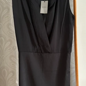 Svart klänning  - Svart klänning med omlott uppe och töjbar material nere. Smickrande på kroppen. 