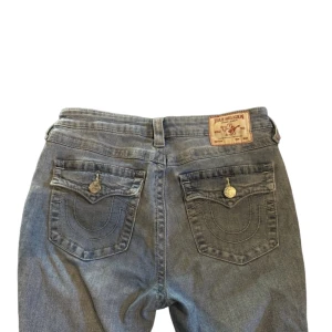 True Religon - Joey Low Rise Flare Jeans  - Ljusblåa Jeans från True Religon. Bakfickor med knappar. Mid Rise Bootcut. Jättefina! Knappt använda. Storlek 30! Priset kan diskuteras vid snabb affär!