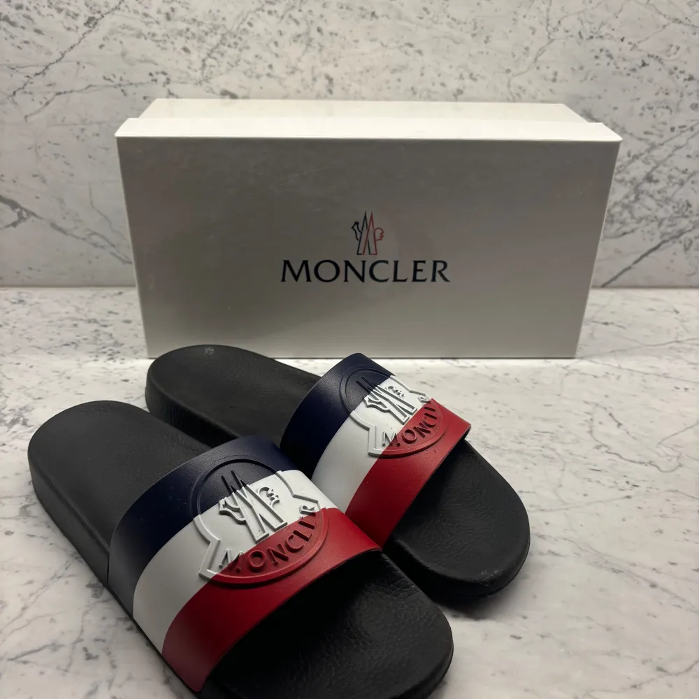 Säljer mina fina Moncler Tofflor/sliders i storlek 44. De är sparsamt använda i jätte fint skick. Inköpta på NK Stockholm för 3000kr. Box ingår självklart och påse till. Hör av dig vid funderingar! Inga Returer.. Skor.