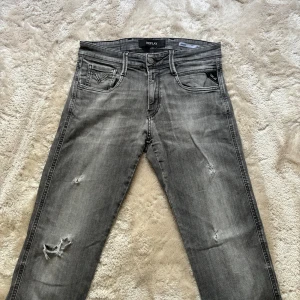Replay Jeans Anbass  - Replay Jeans med slitningar. Skick 6,5/10. Finns tecken på användning. Stolek 29/32. Modell: 180/60kg. Färg svarta/gråa. 