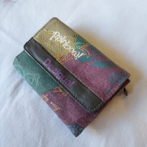 Desigual plånbok - Plånbok från desigual i massa färger, med plats för sedlar, kort och mynt. perfekt skick. 12x9x2,5cm