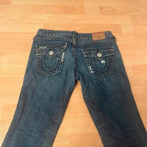 Lågmidjade bootcut true region jeans - Jättesnygga true religion jeans, använda en gång, säljer då de är lite för korta på mig som är 175. Innerbenslängden är 75cm och midjemåttet är 38,5cm. Priset går att diskutera💕