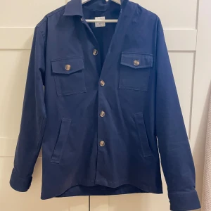 John Henric overshirt - Stilren overshirt från John Henric. Produkten är i storlek M och passar perfekt som utomhusplagg lite kallare höstdagar. Tröjan är i bra skick utan några defekter (9/10). Hör av dig om du har några frågor!