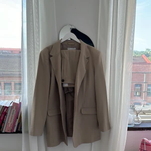 ASOS DESIGN Tall – Kostymsett i naturfärgad beige  - Blazer - Naturfärgad kavaj i boy-modell med smal passform nypris : 520 kr Byxor - 699 kr Blazer + byxor samma färg tillhör samma set . Blazer st.44 , byxor st. 46. Säljer allt för 500 kr 