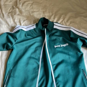Palm angels tröja! - Säljer en snygg grön jacka från Palm Angels. Den har en dragkedja framtill och vita ränder längs ärmarna. Perfekt för en sportig look! Säljer då den inte passar. Passar även S. Pris kan diskuteras vid snabb affär. 