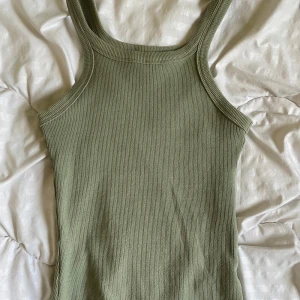 Ribbat linne - Ett ljus grönt ribbat linne. Detta linnet har en lite längre längd än vanliga linnen, för att kunna passa med långmidjade jeans.