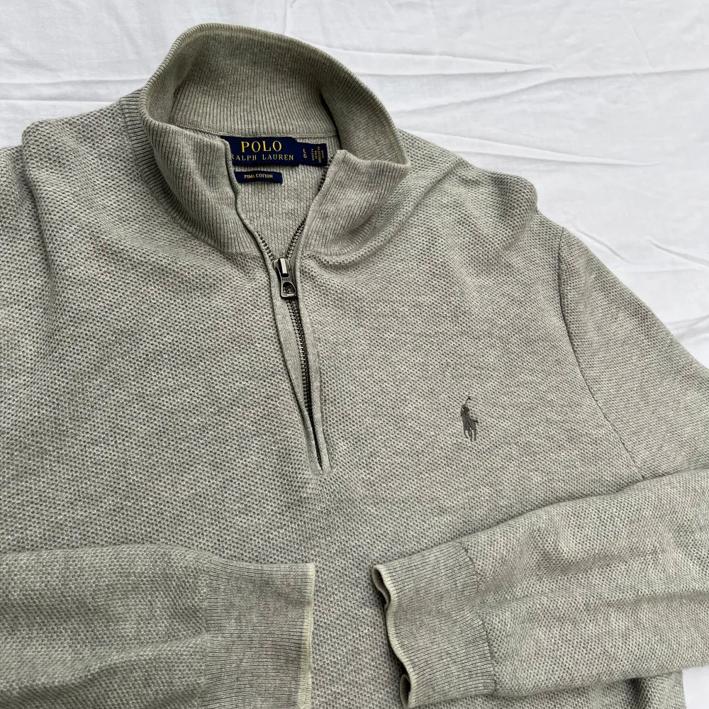 Sparsamt använd och väl omhändertagen. OBS! Den vita bakgrunden får plagget att se mörk och smutsig ut! Stickad half-zip från Polo Ralph Lauren. Tillverkad i bomull i en texturerad stickning. Butikpris: 2 199kr. Stickat.