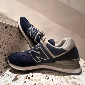 New balance 574 - New Balance 574 i nyskick, använd endast en gång. lätt att matcha med olika outfits. Perfekt för både vardagsbruk och avslappnade tillfällen. Säljes pga för liten storlek. Kontakta mig för mer info!
