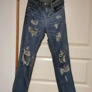 Säljer ett par coola blå jeans från Terranova i storlek S. De har en snygg sliten look med flera revor framtill. Perfekta för en avslappnad och trendig stil. Jeansen är i bra skick och har en klassisk femficksdesign.