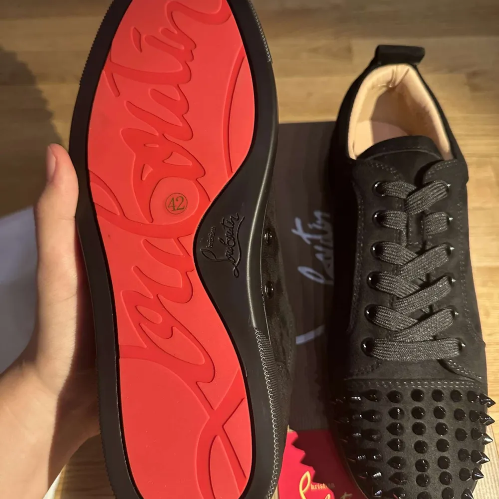 Säljer ett par svarta sneakers i mocka från Christian Louboutin. De har coola nitar på tån och klassisk röd sula. Skorna är i nytt skick och kommer med originalförpackning. Perfekta för att ge din outfit en edgy touch!. Skor.