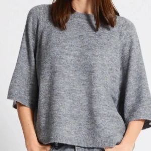Grå stickad tröja - Mysig grå stickad tröja med trekvartsärm. Perfekt för kyliga dagar och ger en avslappnad look. Passar bra till jeans eller kjol för en casual stil.