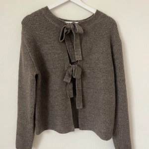 Stickad tröja  - Stickad tröja med fina detaljer. Går att ha  knytningen fram eller bak, då det inte finns någon lapp i nacken (sitter på sidan).