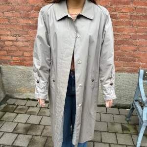 Säljer en stilren beige trenchcoat i bra skick. Den har långa ärmar och knappar framtill. Perfekt för höst och vår, och ger en klassisk look till vilken outfit som helst. Passar både till vardags och lite finare tillfällen.