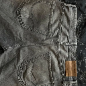 Grå jeans från Jack & Jones - Säljer ett par snygga grå jeans från Jack & Jones i bra skick. De har en klassisk femficksdesign och en knappgylf. Perfekta för både vardag och fest! 🖤