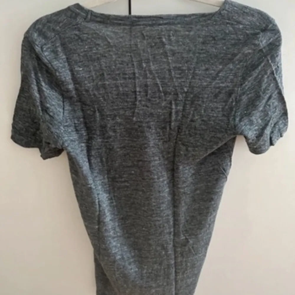 Säljer en snygg grå t-shirt från Isabel Marant Étoile i 100% linne. Den har en v-ringad hals och korta ärmar, perfekt för en avslappnad stil. Toppen är oanvänd och passar både till vardags och festligare tillfällen.. T-shirts.