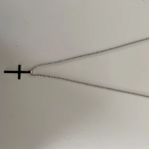Silver kors kedja  - Säljer ett stilrent silverfärgat halsband med ett korshänge. Kedjan är tunn och elegant, perfekt för både vardag och fest. Korset är enkelt och klassiskt, vilket gör det lätt att matcha med olika outfits. Ett måste för den som gillar minimalistisk stil!  AI beskrivning. Fett 