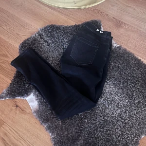 Dondup jeans  - Säljer ett par svarta dundup jeansbyxor i mycket bra skick. De har en slim passform och modellen George, de är perfekta för både vardag och fest. Byxorna har en klassisk design med fem fickor och knappgylf. Passar bra till både t-shirt och skjorta för en stilren look.