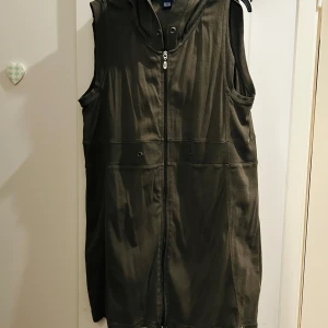 Olivgrön väst från Cecil - Säljer en olivgrön väst från Cecil i storlek M. Västen har en dragkedja framtill och en huva för extra stil och komfort. Perfekt för lager-på-lager under hösten eller våren. Den är i bra skick och redo för nya äventyr!