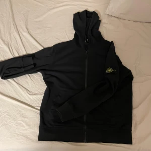 Svart zip up hoodie från Stone Island - Säljer en svart hoodie från Stone Island i mycket bra skick. Den har en dragkedja framtill och en ikonisk logga på ärmen. Perfekt för höst och vår, och den är långärmad för extra värme. Materialet känns mjukt och bekvämt, perfekt för vardagsbruk. Pris kan diskuteras!!!!