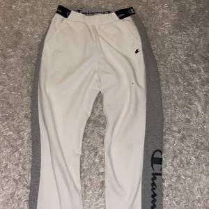 Vita och grå mjukisbyxor - Säljer ett par snygga och bekväma mjukisbyxor från Champion i vitt och grått. Byxorna har en elastisk midja med Champion-logga och grå sidopaneler med stor Champion-text. Perfekta för en avslappnad dag eller träning. 🏋️‍♀️