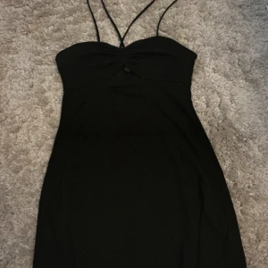 Svart klänning med smala axelband - Säljer en elegant svart axelbandslös klänning med en stilren design. Klänningen har en liten utskärning framtill som ger en extra touch. Perfekt för festliga tillfällen!🖤
