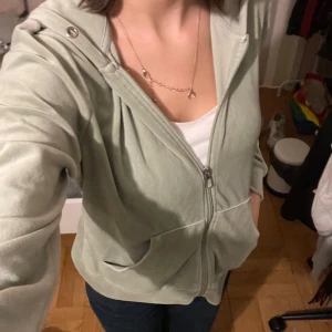 Ljusgrön hoodie med dragkedja - Säljer en supermjuk ljusgrön hoodie med dragkedja framtill. Perfekt för mysiga dagar eller som ett extra lager under hösten. Den har en bekväm passform och en praktisk huva. Fickor på sidorna för att hålla händerna varma eller förvara småsaker. 🧥💚 Storlek M men passar S.