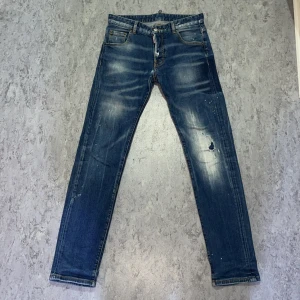 Blå jeans från Dsquared2 - Säljer ett par snygga blå jeans från Dsquared2 i storlek 46. De har en cool slitning och en vintage look med ljusa partier. Perfekta för en avslappnad stil. Tillverkade i Italien med hög kvalitet. Passar både till vardags och fest!