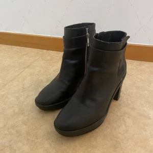 Pull&Bear - Snygga svarta boots i skinn med dragkedja på sidan. De har en stabil klack och en rund tå, perfekt för både vardag och fest. Skorna är i bra skick. Enkla att matcha med olika outfits! Märket är Pull&Bear