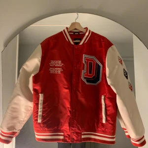 Röd och vit bomberjacka med broderier - Säljer en snygg röd och vit bomberjacka från Zara i storlek  XL. Jackan har coola broderier på både fram- och baksidan samt på ärmarna. Den har långa ärmar och stängs med knappar. Perfekt för höst och vår!